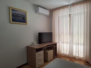 a room with a television on a desk with a window at Apartments and Rooms Vinko in Barbat na Rabu