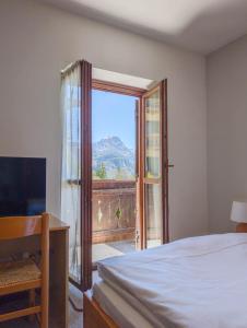 a bedroom with a bed and a window with a view at Leres Pastry Hotel in Sottoguda