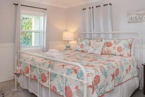a white bedroom with a bed with a floral bedspread at Deja Blue by Pristine Properties Vacation Rentals in Mexico Beach