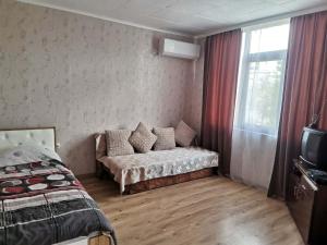 a bedroom with a bed and a couch and a window at Студио Търговище in Targovishte