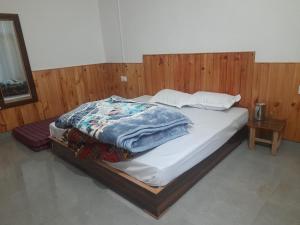 a bed in a room with a wooden wall at Dholadhar Hotel & Restaurant in Barot 