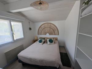 a small bedroom with a bed and a chandelier at Maisonnette chez Laurette in Saint-Martin-de-Seignanx