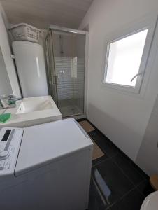 a white bathroom with a sink and a window at Maisonnette chez Laurette in Saint-Martin-de-Seignanx
