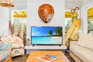 a living room with a tv and a surfboard at Quarters B by Pristine Properties in Mexico Beach