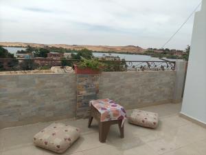a bench and ottomans on a balcony with a view at sunset in Abu Simbel