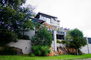 a house on a hill with a fence and trees at AB&AB Guesthouse Bedfordview in Germiston