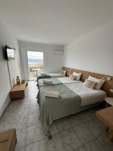 a bedroom with three beds and a large window at Sea View Luxury Studios in Vrachonisída Palaiókastro