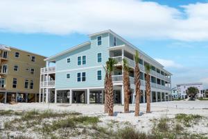 a blue building with palm trees in front of it at Pelican Roost E by Pristine Properties Vacation Rentals in Mexico Beach