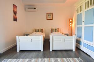 two white beds in a room with a rug at Pike Inn Bucătărie Autentică & Cazare cu Farmec in Dunavăţu de Sus +66 photos