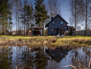 a house with a pond in front of it at Domki u Danusi z widokiem na wodę in Lipusz