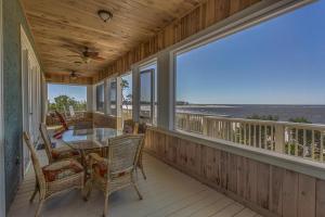 a screened porch with a table and chairs and the ocean at Island Idyl by Pristine Properties Vacation Rentals in Indian Pass