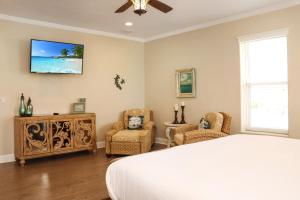 a bedroom with a bed and two chairs and a tv at Farr Away Living by Pristine Properties Vacation Rentals in Indian Pass