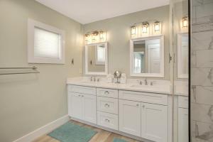a white bathroom with two sinks and a shower at Shore Looks Good by Pristine Properties Vacation Rentals in Mexico Beach +88 photos