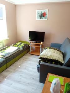 a living room with two beds and a flat screen tv at OLEŃKA in Darlowko