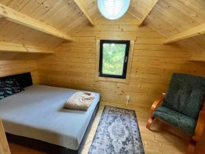 a bedroom with a bed and a chair in a log cabin at Dom nad Saskiem 3 sypialnie, jacuzzi-relaks, natura i komfort in Linowo
