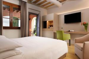 a bedroom with a large white bed and a desk at Borgobrufa Spa Resort Adults Only in Brufa