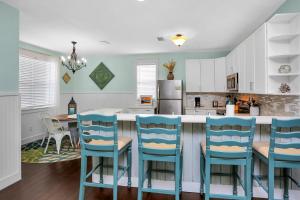 a kitchen with blue chairs and a kitchen island at Barefoot Cottage D133 - Beachy Keen by Pristine Properties Vacation Rentals in Highland View