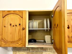 a wooden cabinet with plates and utensils in it at A DUE PASSI da BARI - La Casa della Nonna al 39 in Noicattaro