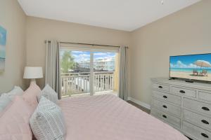 a bedroom with a bed and a television and a balcony at Waterside Village Condo 203 by Pristine Properties Vacation Rentals in Mexico Beach +56 photos
