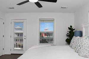 a white bedroom with a bed with a ceiling fan at The Ricks Carlton by Pristine Properties Vacation Rentals in Mexico Beach