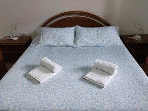 a bed with two towels on top of it at Casa delle Rose Terrazza vista mare panoramica e relax a Cala Gonnone, WiFi, AC in Cala Gonone