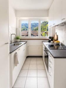 a white kitchen with a sink and two windows at 3Br Topview Interlaken Mountain View Apartment in Unterseen