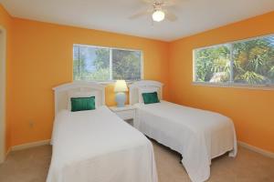 two beds in a room with orange walls and windows at Boardwalk Sandpiper by Pristine Properties Vacation Rentals in Cape San Blas +46 photos