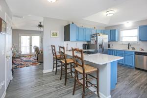 a kitchen with blue cabinets and bar stools at Flamingo Roost by Pristine Properties Vacation Rentals in Indian Pass