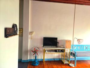 a room with a desk with a computer and a fan at west water hostel in Ban Khouaphan