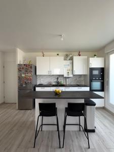 a kitchen with white cabinets and a counter with two chairs at T2 cosy proche Versailles in Trappes