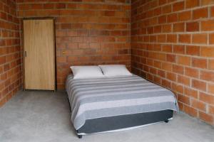 a bed in a brick room with a brick wall at Chácara Morada do Sol Ibiúna in Ibiúna