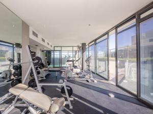 a gym with treadmills and ellipticals in a building with windows at Infinity Self Catering Apartments in Bloubergstrand