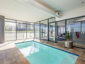 a swimming pool in a building with glass walls at Infinity Self Catering Apartments in Bloubergstrand