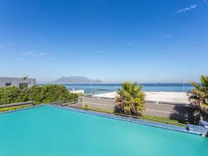 a swimming pool with a view of the ocean at Infinity Self Catering Apartments in Bloubergstrand