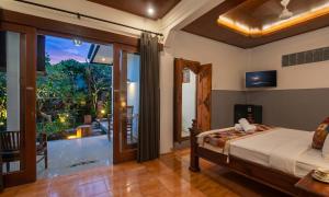 a bedroom with a bed and a large window at Pondok Taksu Bali in Kuta