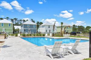 a swimming pool with two lawn chairs and houses at Keys to the Cape by Pristine Properties Vacation Rentals in Cape San Blas