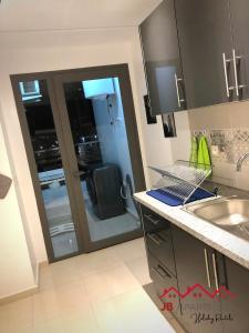 a kitchen with a sink and a sliding glass door at JB Apartment -B18- in Kenitra