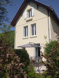 a white house with a table and an umbrella at Gite La maison du gardien in Marcillac-Vallon