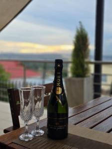 a bottle of wine and two glasses on a wooden table at AB&AB Guesthouse Bedfordview in Germiston