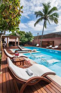 a swimming pool with chaise lounge chairs on a wooden deck at Pousada Quarto Crescente in Trancoso