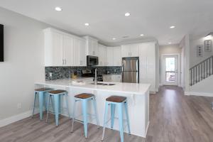a kitchen with white cabinets and bar stools at Beach Fantasies A by Pristine Properties Vacation Rentals in Mexico Beach +39 photos