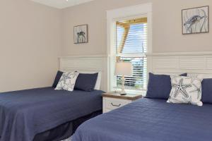 a bedroom with two beds with blue sheets and a window at The Great White 2 by Pristine Properties Vacation Rentals in Beacon Hill