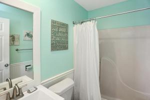 a bathroom with a white shower curtain and a sink at Edgewater Retreat by Pristine Properties Vacation Rentals in Cape San Blas +51 photos