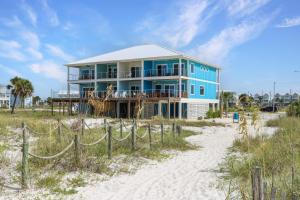 a blue house on the beach with a sandy beach at Sea La Vie by Pristine Properties Vacation Rentals in Mexico Beach