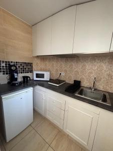 a kitchen with white cabinets and a sink and a microwave at Maisonnette au calme-proche Métro in Maisons-Alfort
