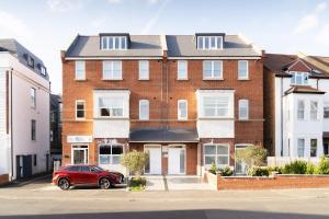 a red car parked in front of a brick building at Stylish 2BR Flat by Richmond Park in Kingston upon Thames