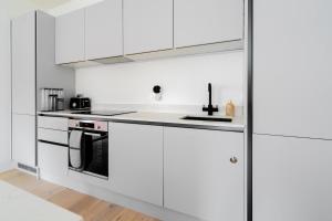 a white kitchen with white cabinets and appliances at Stylish 2BR Flat by Richmond Park in Kingston upon Thames