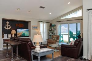 a living room with leather furniture and a large window at WindScape by Pristine Properties Vacation Rentals in Indian Pass