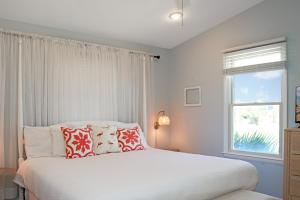 a bedroom with a white bed with pillows and a window at WindScape by Pristine Properties Vacation Rentals in Indian Pass