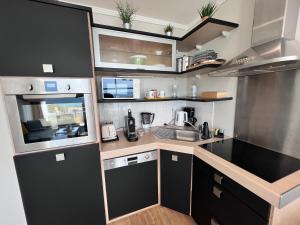 a small kitchen with black cabinets and a sink at Les Pierres Marines in Le Conquet +12 photos